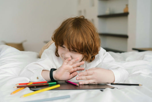 A young child engaging in a sensory activity with a colorful bin filled with rice, toys, and small objects, promoting motor skills and sensory exploration for children with autism and developmental delays.